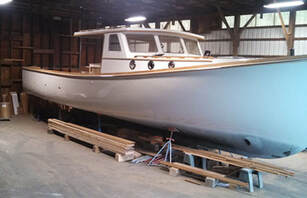 Downeast wooden power boat twist in south shore boatworks shop being refit and restored