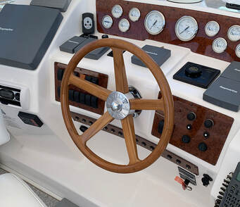 wooden powerboat steering wheel installed at the helm of a powerboat with a chromed bronze hub and figergrips